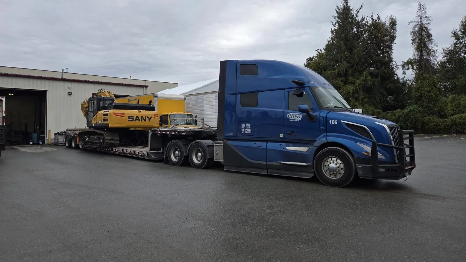 Speedgo Transport truck with a SANY excavator outside a warehouse at the yard