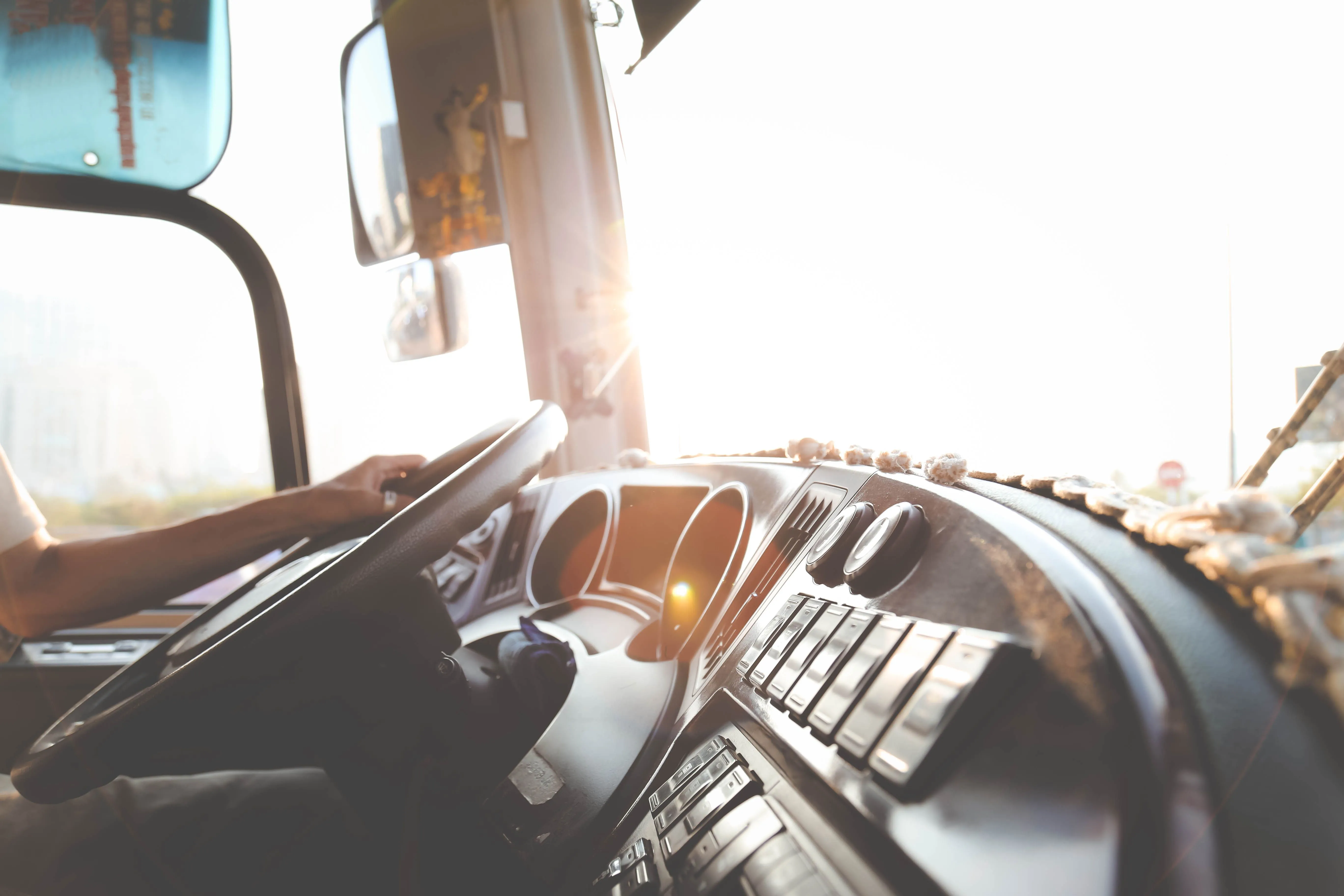 Driver's hand on the steering wheel of a truck cab